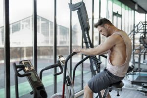 Focused man working out on a stationary bike in a modern gym.